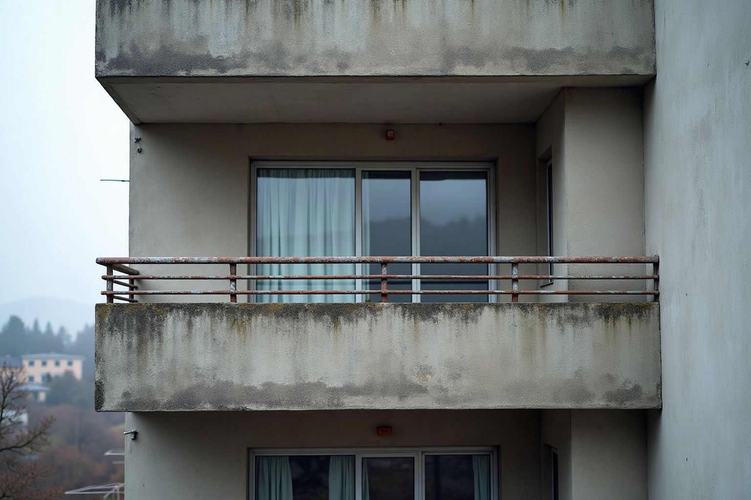 Ancien garde-corps bas à lisses horizontales sur un balcon en béton des années 1960
